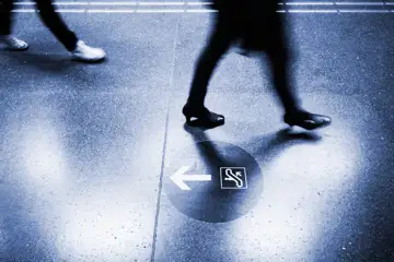 Kvinnoben går i ett stationshus eller liknande, en pil på golvet visar motsatt riktning
