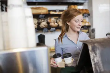 Ung kvinna står bakom disken på ett kafé