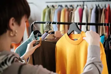 Kvinna tittar på kläder som hänger på en stång i en butik