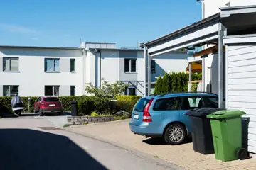 Gata med radhus och bil parkerad på uppfarten.