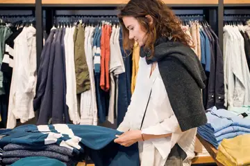 Kvinna tittar på stickade tröjor i en butik