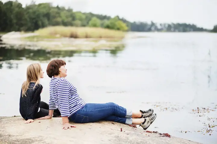 Två personer som sitter på klippa och blickar ut över en sjö