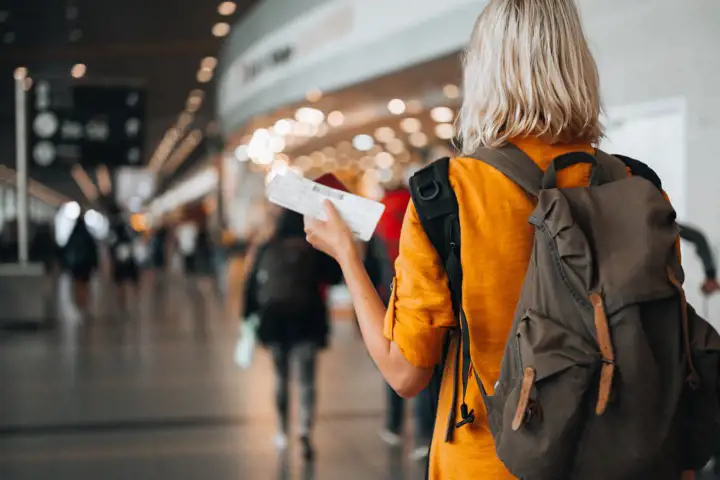 Kvinna på flygplats som går mot gaten med pass och boardingkort i handen