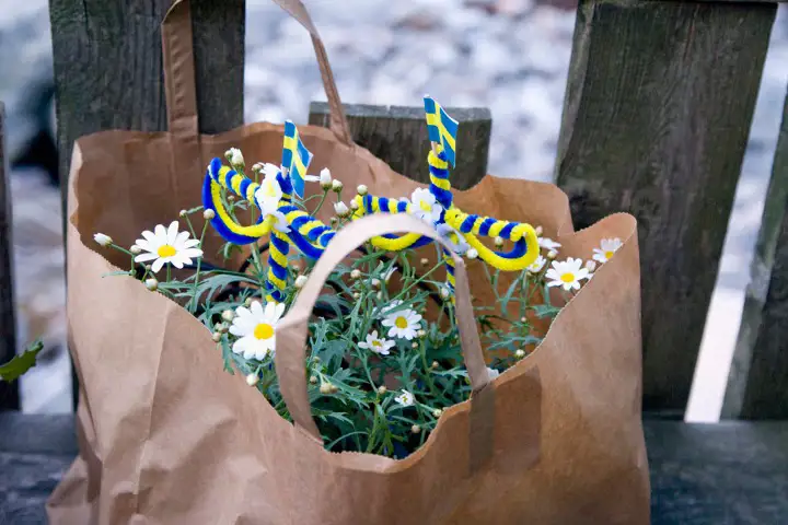 Papperskasse med blommor och små blågula midsommarstänger