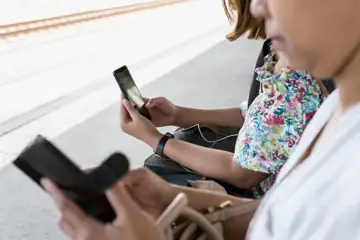 Personer sitter på rad och tittar på mobilskärmar