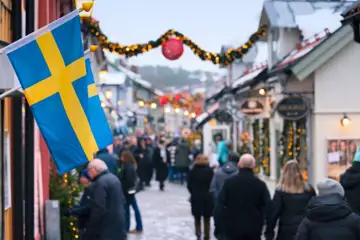 Shoppinggata i julskrud med svenska flaggan i förgrunden