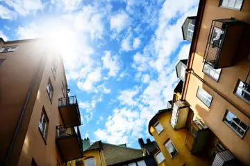 Bild från innergård tagen vid marken så att den blåa himlen syns mellan husen