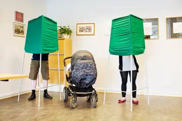 Människor bakom valbås i röstningslokalen